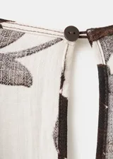 Jardinera enterito de corte recto y largo, con estampado floral en tonos marrón y fondo beige. Presenta cuello en V, manga corta, cinturón incorporado con hebilla en la cintura y cierre de cremallera en la parte posterior.