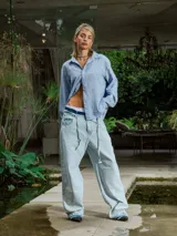 Camisa de lino rayada en tonos celeste y blanco, con cuello y botones frontales. Presenta un estampado en el frente y la espalda.