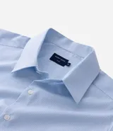 Camisa de manga larga color celeste, con cuello inglés y abotonado delantero. Confeccionada en tricolina con fibra de bambú, presenta un diseño maquinetado con estampado de rayas.