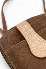 Bandolera marrón de diseño rectangular vertical con bolsillo frontal y solapa con cierre de botón a presión. Cuenta con correa larga ajustable para llevar al hombro o cruzada.
