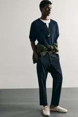 Pantalón chino negro slim fit de corte recto, con bolsillos frontales, trabillas para cinturón y cierre frontal con cremallera y botón.