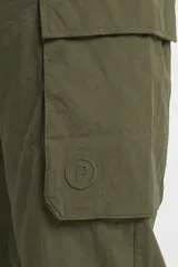 Pantalón cargo de nylon color beige, con elástico en la cintura y en los puños. Presenta bolsillos laterales con solapa y un logo de goma aplicado en uno de ellos.