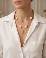 Collar de acero con baño de oro, compuesto por una cadena de eslabones finos intercalados con perlas naturales y un dije circular central con diseño de árbol de la vida y borde con incrustaciones de circonias.