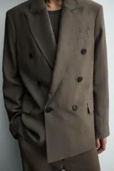 Blazer Zara de corte relajado confeccionada en mezcla de viscosa y lino. Presenta cuello con solapas de pico, cierre frontal de botonadura cruzada, bolsillos de solapa en la cadera y aberturas en la espalda.