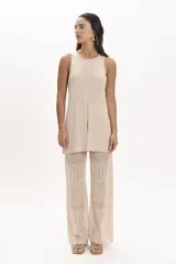 Blusa beige de tejido de punto con cuello redondo y sin mangas. Presenta un tajo central en el frente.