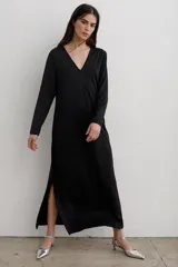 Vestido largo de corte recto con escote en V y mangas largas. Presenta un estampado abstracto en tonos rojos, naranjas y negros, con tajos laterales en el ruedo.