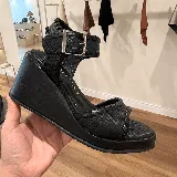 Sandalias negras con plataforma y tobillera con hebilla metálica.