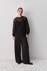 Sweater calado de punto negro, con cuello redondo y mangas largas, de diseño liviano ideal para superposiciones.