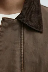 Cazadora de corte relajado con acabado efecto encerado, cuello de solapa en pana, manga larga y bolsillos frontales de plastrón con solapa. Presenta cierre frontal de cremallera oculta por solapa con botones a presión.