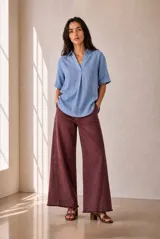 Blusa de lino color azul melange, de corte holgado, con cuello en V, mangas cortas con vuelta y dobladillo redondeado.
