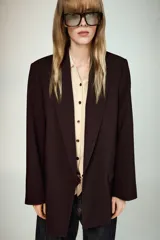 Chaqueta de punto de corte clásico, color gris, con cuello solapa, manga larga y cierre frontal con botones a contraste.