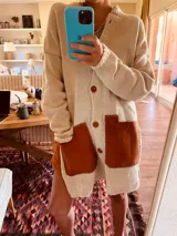 Cardigan de lana color crudo con bolsillos de cuero color marrón y botones de madera.