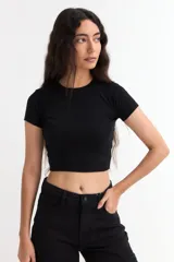 Remera crop negra de tejido acanalado, con cuello redondo a la base y mangas corta.