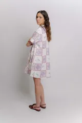 Vestido corto beige con estampado botánico en negro, cuello camisero, mangas cortas y cierre frontal con botones.