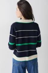 Buzo de punto estilo polo, con diseño a rayas horizontales en azul marino, verde y crema. Presenta cuello camisero con cierre frontal de tres botones, mangas largas y puños acanalados. Incluye el logo de la marca bordado en el pecho.