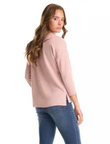 Buzo de punto de alta densidad con tacto aterciopelado, color rosa. Presenta escote a la base, mangas tres cuartos y hombros caídos. Su diseño es minimalista, con calce recto y holgado, y cuenta con pequeños tajos laterales en el ruedo.