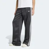 Pantalón deportivo Adidas Satin Loose de corte holgado, color negro con las icónicas tres tiras blancas a los lados y el logo del trifolio bordado. Confeccionado en tejido satinado con diseño de perneras anchas.