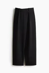 Pantalón sastrero negro de corte holgado, con diseño cruzado asimétrico en el frente, pinzas y piernas amplias.