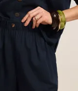 Short runner de viscolino, con cintura elástica, botón decorativo y bolsillos laterales. Presenta un corte evasé holgado con bajo redondeado.