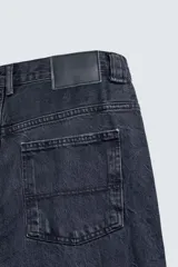 Jeans relaxed fit de corte holgado y amplio en toda la pierna, color negro con efecto lavado. Presenta tiro medio, bolsillos frontales, bolsillos traseros de plastrón y aplicación de tira multifunción en la pernera. Cierre frontal con cremallera y botón.