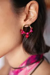 Aro tipo argolla de 2 cm de diámetro, decorado con cuentas de vidrio facetadas en tonos fucsia, rojo y negro, montadas sobre una base de bronce.