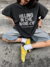 Remera gris con efecto acid wash y diseño oversize. Presenta un estampado frontal con la inscripción "KILLING IN THE NAME OF" y la frase "NOW YOU DO WHAT THEY TOLD YA".