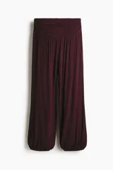 Pantalón globo color bordó, de corte holgado en punto de viscosa, con cintura elástica ancha fruncida y piernas fruncidas con elástico en los tobillos.