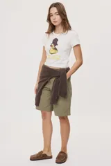 Remera blanca de manga corta, con estampa frontal de un pato de hule con turbante y labios pintados, acompañada de la frase "In all else fails, denial".