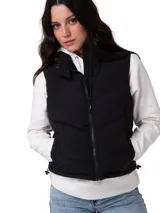 Chaleco acolchado tipo puffer color negro, con cierre frontal de cremallera, cuello alto protector y bolsillos laterales con cierre. Presenta un diseño técnico resistente al agua y al viento con forro interno estampado.