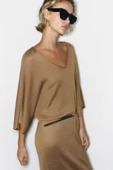 Vestido midi de punto color marrón con escote en V, mangas anchas y diseño holgado. Incluye un cinturón delgado marrón con hebilla metálica.