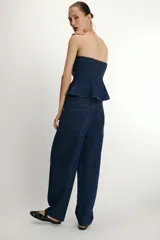 Pantalón de jean azul oscuro con corte tipo ballon, tiro alto, cierre frontal con cremallera y botón metálico, bolsillos delanteros y traseros.