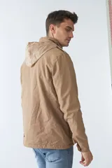 Campera de gabardina verde militar con capucha desmontable y ajustable, cierre frontal con cremallera y múltiples bolsillos con solapa.