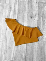 Top corto con un solo hombro y volado grande.