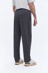 Pantalón de jogging con corte recto y ajuste relajado, confeccionado en tejido de algodón y poliéster. Cuenta con cintura elástica con cordón de ajuste y bolsillos laterales funcionales.