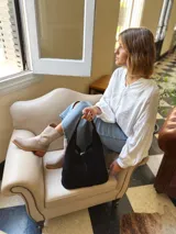 Bolso tipo tote bag negro de cuero, con costuras a la vista y manijas cortas.