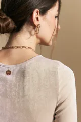 Top de manga larga con textura suave y leve brillo. Presenta una silueta al cuerpo, tajos laterales y terminaciones onduladas en el ruedo.