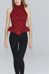 Corset bordó de cuello halter con hombros descubiertos, confeccionado con combinación de tejidos con patrón floral, detalles de volados en las sisas y bajo en peplum. Cuenta con cierre en la espalda con cremallera.