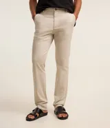 Pantalón slim de sarga color beige, de corte ajustado, con cierre frontal de botón y cremallera, y bolsillos laterales tipo cuchillo.