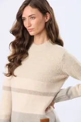 Buzo tejido de abrigo con cuello redondo y diseño a rayas horizontales en tonos suaves de beige y gris.