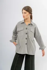 Sobrecamisa de paño color gris, con cuello camisero, cierre frontal de botones oscuros y dos bolsillos frontales con solapa. Presenta mangas largas con puños ajustables y un corte holgado.