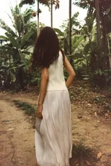 Chaleco color crema de punto, con escote en pico y sin mangas. Cierre cruzado frontal con lazada lateral.