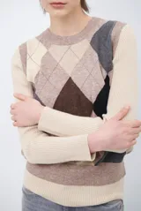 Chaleco de punto con diseño de rombos en tonos beige, marrón y gris. Presenta cuello redondo y corte ajustado a la cintura.