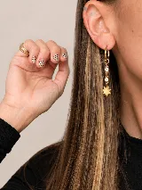 Aros colgantes dorados de argolla con dijes de cadena corta adornados con pequeñas circonias circulares y una estrella de ocho puntas en el extremo.