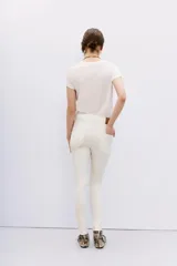 Jean tiro alto, calce skinny, color blanco, con acabado símil cuero y pierna ajustada hasta el tobillo.