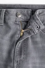 Jeans de tiro alto, color gris oscuro lavado, con corte ajustado en la parte superior y pierna acampanada (flare) desde la rodilla hasta el bajo. Presenta cinco bolsillos y cierre frontal con botón.