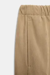 Pantalón de tiro medio color beige, de pierna ancha y corte recto. Cuenta con cintura elástica ajustable con cordones y bolsillos frontales.