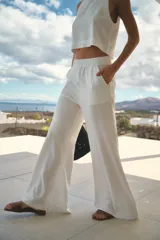 Pantalón de lino color blanco, de tiro alto y corte oxford con perneras amplias. Cuenta con cintura elastizada y bolsillos laterales.