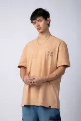 Remera de corte semi-oversize en color naranja con efecto de lavado tipo snow. Presenta un pequeño estampado gráfico en el pecho y cuello redondo.