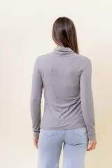 Polera blanca de manga larga y calce al cuerpo, confeccionada en tejido suave, liviano y elástico, con cuello alto.