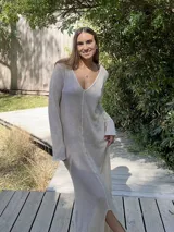 Vestido largo color crudo, de tejido de algodón fino y ligero, con escote en V y mangas largas acampanadas. Se puede usar con el escote hacia adelante o hacia atrás.